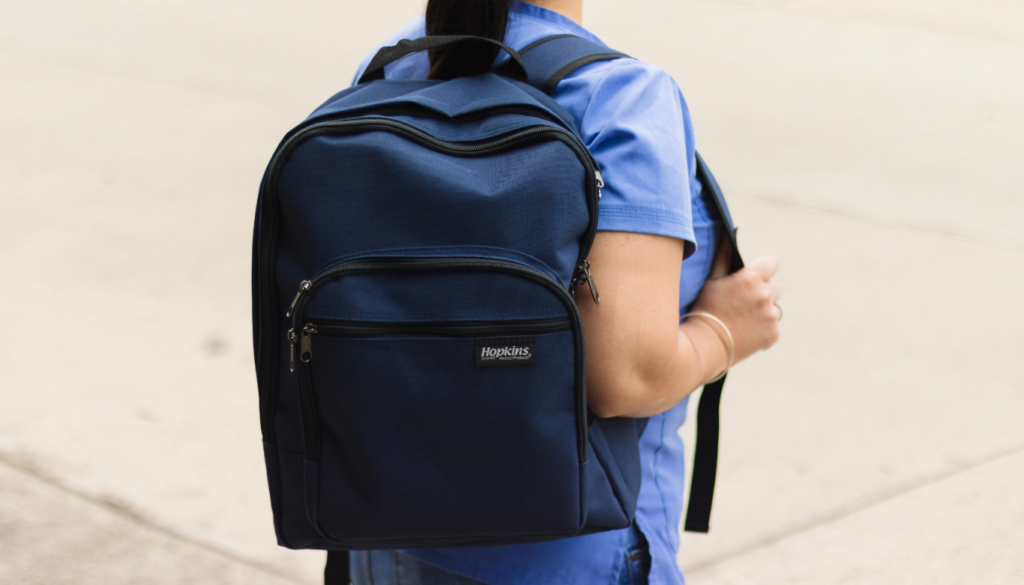 dana-st-dental-back-to-school | Dana Street Dental Person wearing a navy blue backpack over blue clothing, standing outdoors on a concrete surface.